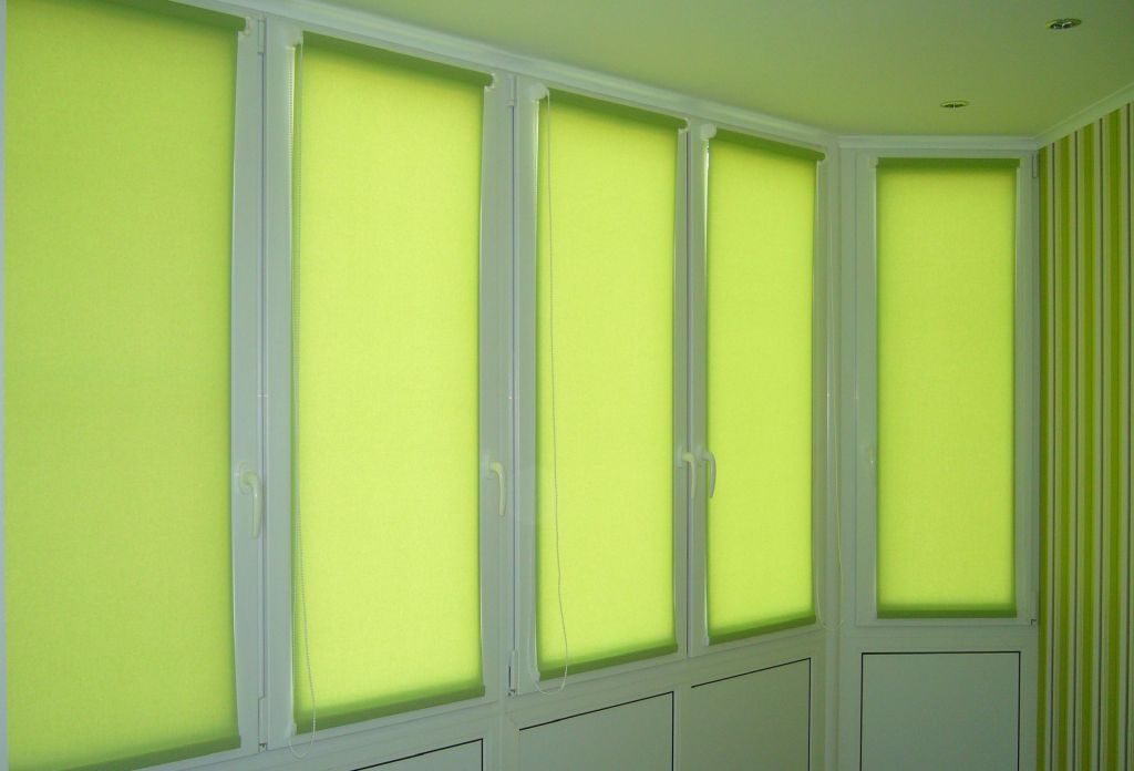 Закрытые рулонные шторы на пластиковом окне балкона