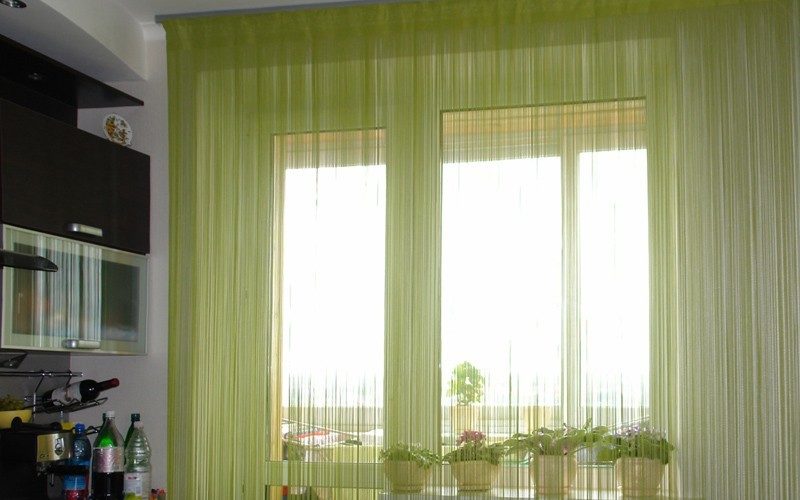 Зеленые нитяные шторы на кухне с балконом